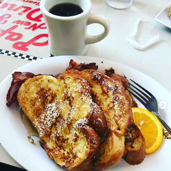 French toast with powdered sugar, bacon, and an orange slice, with coffee at Papa's New York Diner.